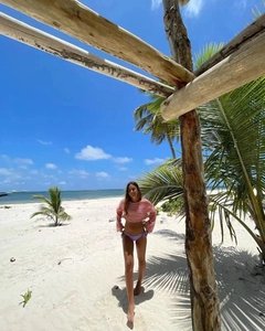 Gros plan d'un haut court au crochet à manches longues dans un décor de plage tropicale