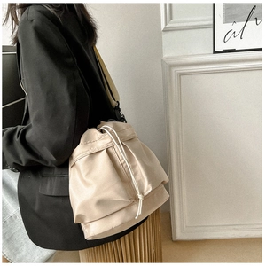 Zijaanzicht van de beige nylon bucketbag met trekkoord op model voor casual gebruik