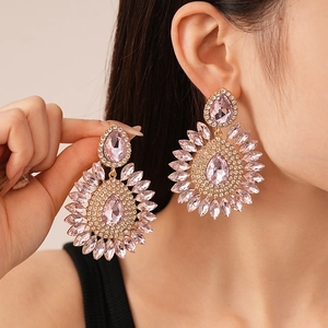 Close-up of pink crystal teardrop earrings with oversized sunflower design and silver needles