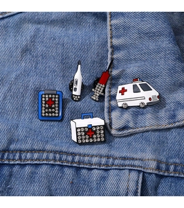 Close-up of five medical enamel pins with rhinestones on a blue denim jacket pocket