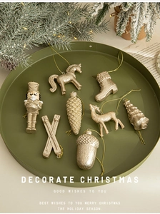 Flat lay of gold Christmas ornaments including nutcracker and deer on green plate