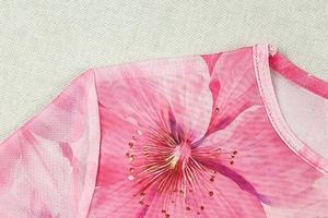 Détail du tissu en maille rose à fleurs montrant les coutures et la texture transparente