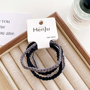 Close-up of black and grey woven elastic hair bands on a display card and wooden tray