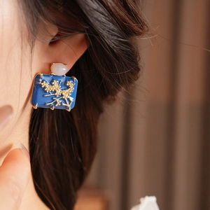 Detailed close-up of a vintage blue enamel rectangular earring worn by a model