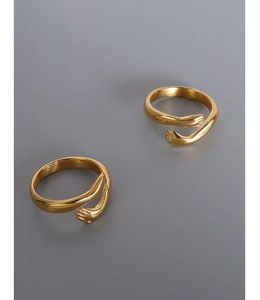 Macro detail of gold-plated hugging hands open ring with smooth metallic texture