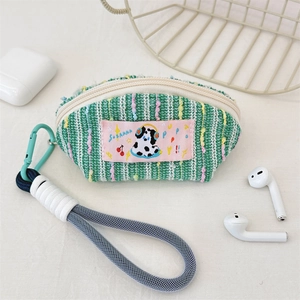 Detail of tweed earphone pouch showing green knit texture and mint green carabiner clip