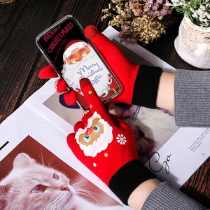 Winter touch screen knitted gloves with Santa pattern using a phone in a cozy setting
