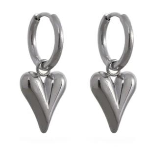 Close-up of polished silver 3D heart drop earrings on a minimalist white background