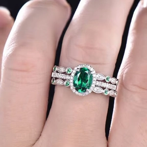 Close-up of three-piece luxury ring set with oval emerald gemstone and leaf patterns