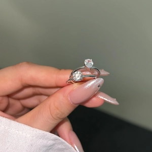 Detailed view of silver rings featuring round and pear-cut zircon stones on a hand