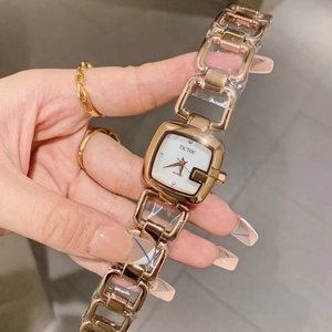 Detailed close-up of rose gold square watch dial with a hollow bracelet chain design