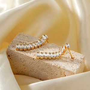 Elegant gold-plated ear climbers with sparkling zircon stones on natural stone and silk