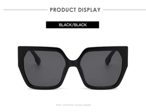 Detail shot of oversized square black frame sunglasses with dark lenses and logo lettering