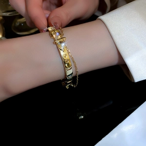 Detailed shot of a gold belt buckle bangle with pavé zircons and delicate adjustment chain
