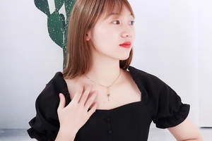 Close-up of a gold heart and key pendant necklace worn on a female model