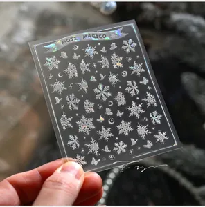 Close-up of laser snowflake and butterfly nail stickers with holographic shimmer effects