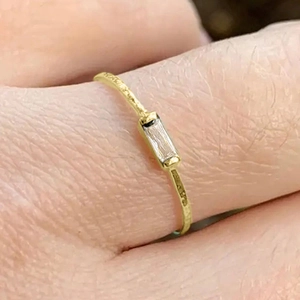 Macro shot of minimalist gold ring with rectangle zircon and hammered texture detail