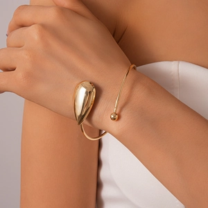 Gros plan détaillé d'un bracelet manchette goutte doré poli porté par un mannequin