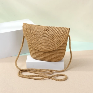 Detail of hand-woven straw crossbody bag with natural texture and beige geometric design