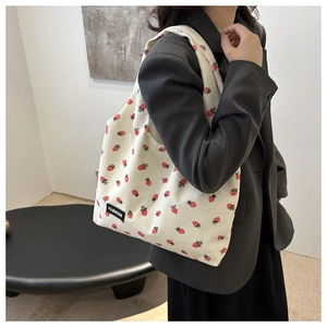 Detail of soft corduroy tote bag featuring red strawberry print and fashion label