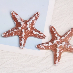 Macro detail of two resin starfish ornaments with white dots on a blue and white background