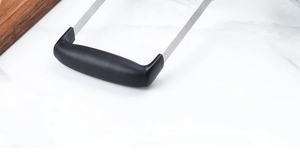 Gros plan sur la poignée noire ergonomique et le cadre en acier inoxydable du presse-purée