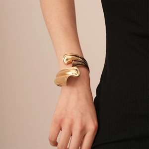 Golden wavy sculpture cuff bracelet for women with minimalist metallic geometric design