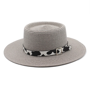Detailed close-up of grey woven straw boater hat with cow print ribbon and metal buckle
