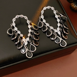 Detailed view of silver tassel earrings with black teardrop crystals on black leather