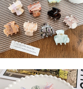 Detailed close-up of marble pattern acrylic hair claws in assorted elegant colors