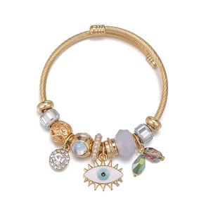 Gold evil eye charm bangle featuring multi-element crystal beads and twisted steel cable