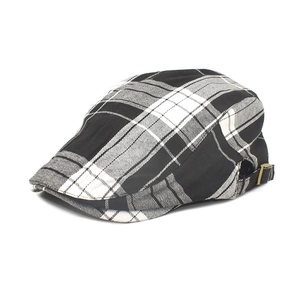Detail of adjustable bronze metal buckle on classic black and white plaid forward cap