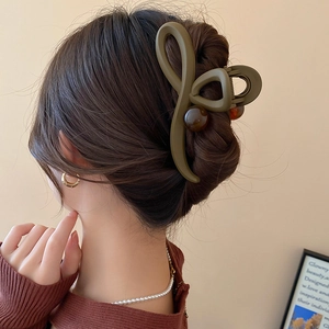 Détail d'une grande pince à cheveux fleur verte olive sur des cheveux bruns