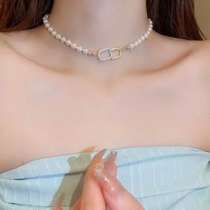 Choker élégant en perles avec boucle nez de porc dorée et détails en zircons brillants