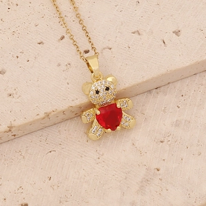 Golden bear necklace with a red heart gemstone and sparkling zircon stones on a stone base
