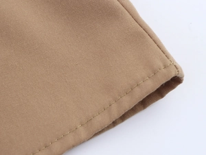 Close-up of khaki woven fabric with detailed double stitching and hem finish