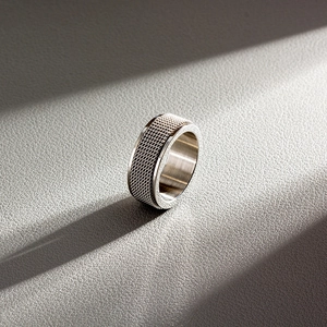 Macro detail of 8mm silver steel spinning ring showing grid texture on leather surface