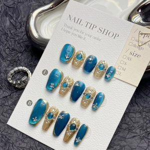 Detail of luxury deep blue cat-eye handmade press-on nails with champagne gold accents