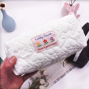 Detail of white quilted heart cosmetic bag with Lucky Flower label and soft cotton texture