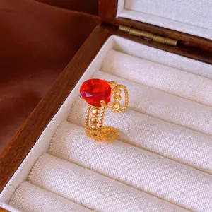 Vintage gold-plated stainless steel ring with oval red gemstone in a wooden jewelry box