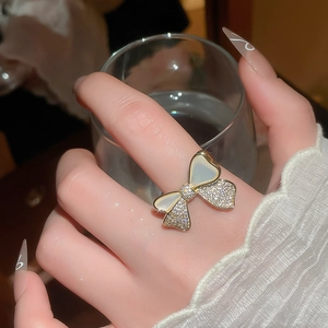 Detailed view of 14k gold bow ring with sparkling zircons and white shell petals