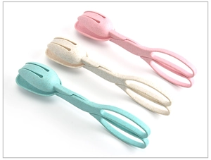 Three wheat straw salad tongs in pink, beige, and green colors on a white background