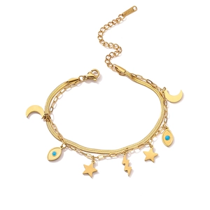 Detail of gold double-layer chain bracelet featuring crescent moon and evil eye charms