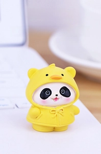 Close-up of a cute panda figurine wearing a yellow duck raincoat on a laptop keyboard