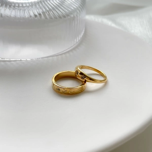 Star and moon engraved gold rings with zircon stones on a white ceramic plate