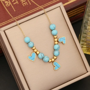 Golden chain necklace with turquoise beads and heart pendants in a beige jewelry box