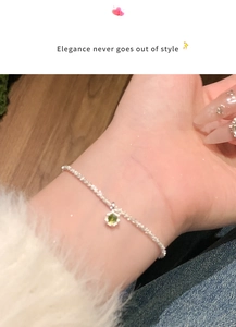 Silver delicate chain bracelet with a green floral gemstone pendant worn by a person