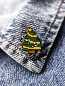 Macro detail of I LOVE CHRISTMAS enamel tree pin on blue denim fabric collar