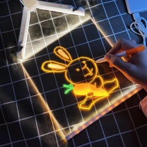 Close-up of a hand drawing a glowing rabbit on a transparent LED writing board with USB cable