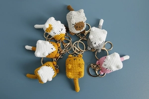 Flat lay of colorful handmade crochet cat keychains with diverse knit patterns